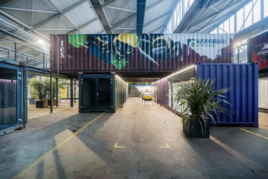 Gasse zwischen bunten Überseecontainern in der Halle des hive – in den Containern liegen Büros und Workshopräume.