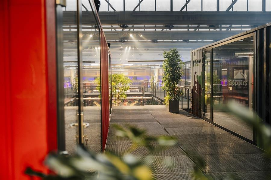 Blick durch die Glasfronten der Container in die offene Halle.